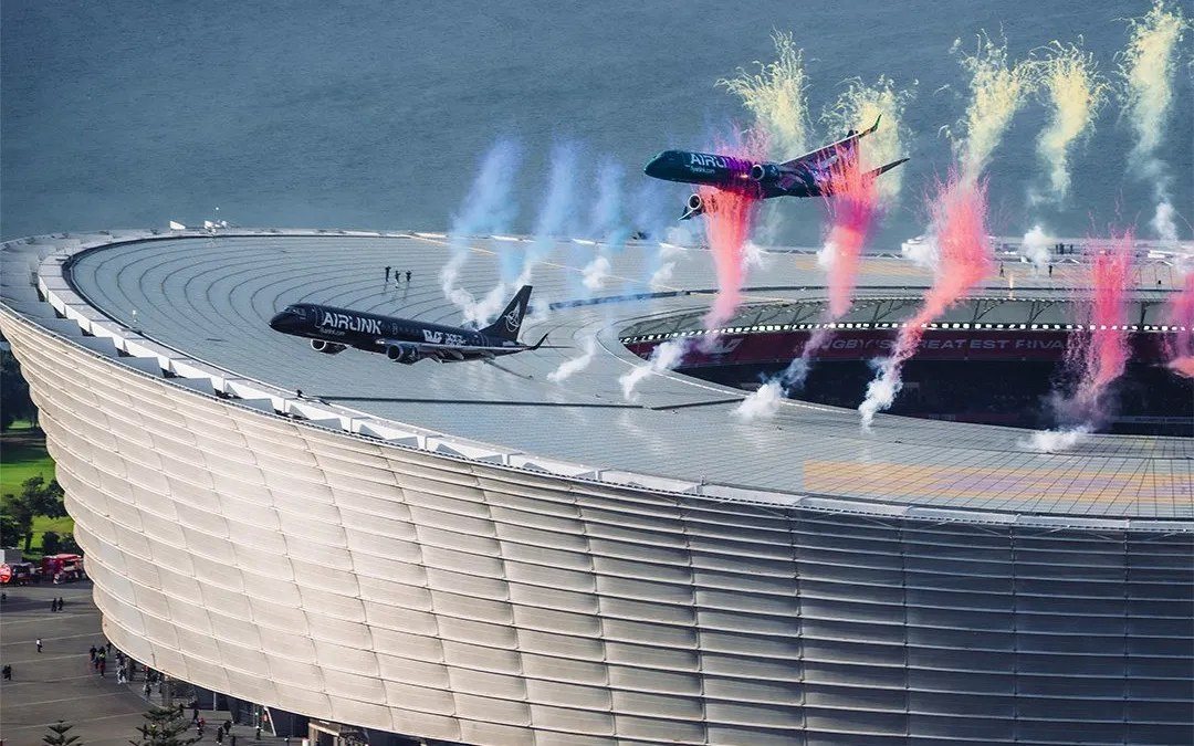 Two Airlink jets passing low over DHL Stadium in Cape Town, with pyrotechnics firing from the roof