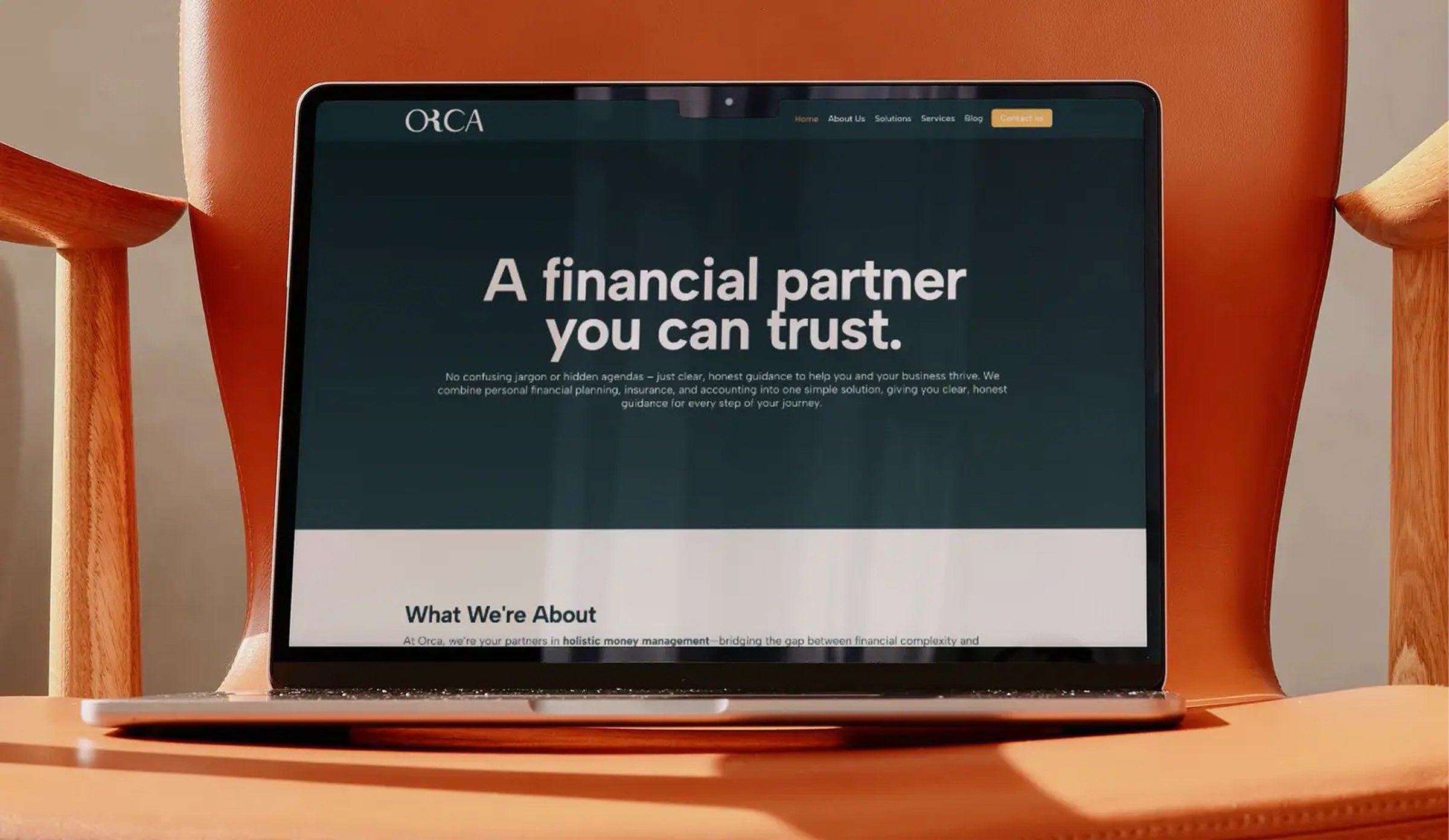 The Orca Consult site on a laptop, orange chair